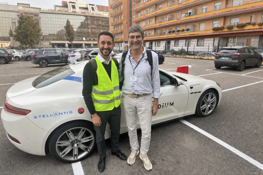 Harilaos Vasiliadis with Jordi Casademont, Professor at UPC, alongside the Stellantis CRF autonomous vehicle at the final Harilaos Vasiliadis con Jordi Casademont, profesor de la UPC, junto al vehículo autónomo de Stellantis CRF en la demonstration of the PoDIUM project in Turin demonstración final del Proyecto PoDIU